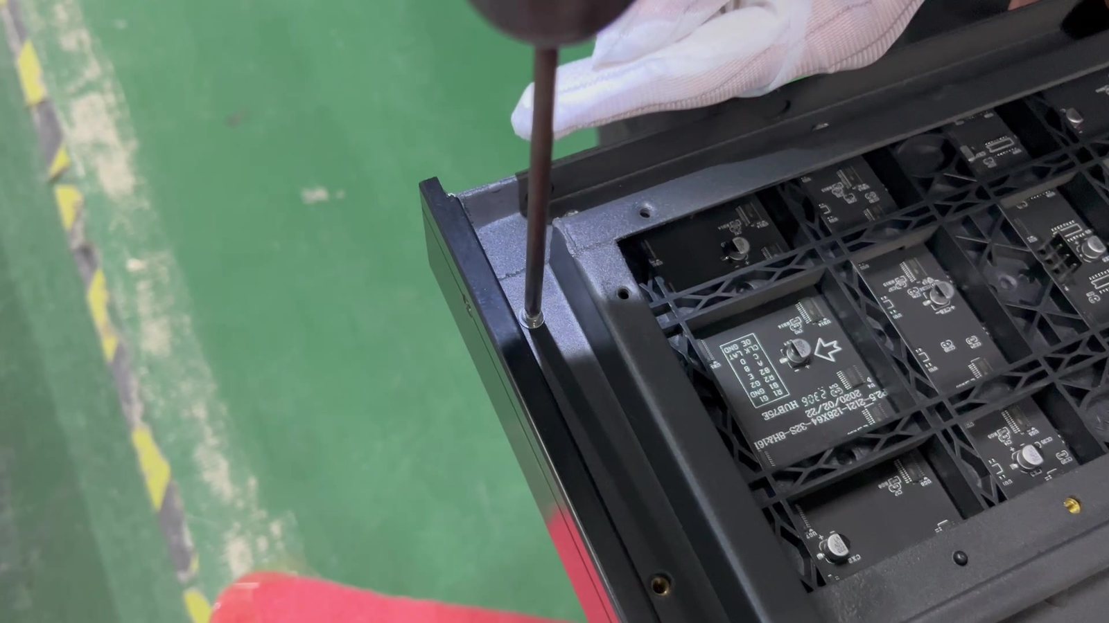Hand removing an LED module from the front of a die-cast poster with a suction cup